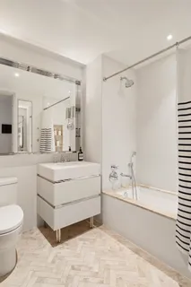 a bathroom with a white tub shower vanity and a sink
