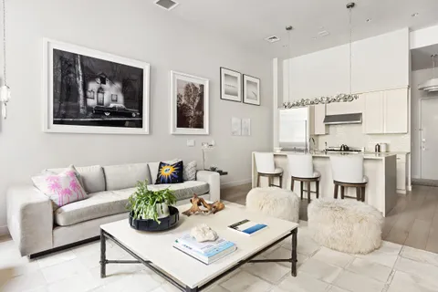 a living room with furniture a rug kitchen view and a table