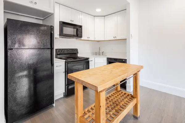 a kitchen with stainless steel appliances granite countertop a refrigerator a stove and a sink with wooden floor