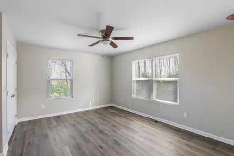a view of empty room with wooden floor and fan