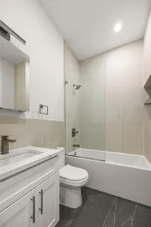 a bathroom with a granite countertop sink a toilet and a shower