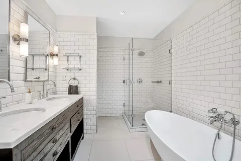a spacious bathroom with a tub sink and mirror