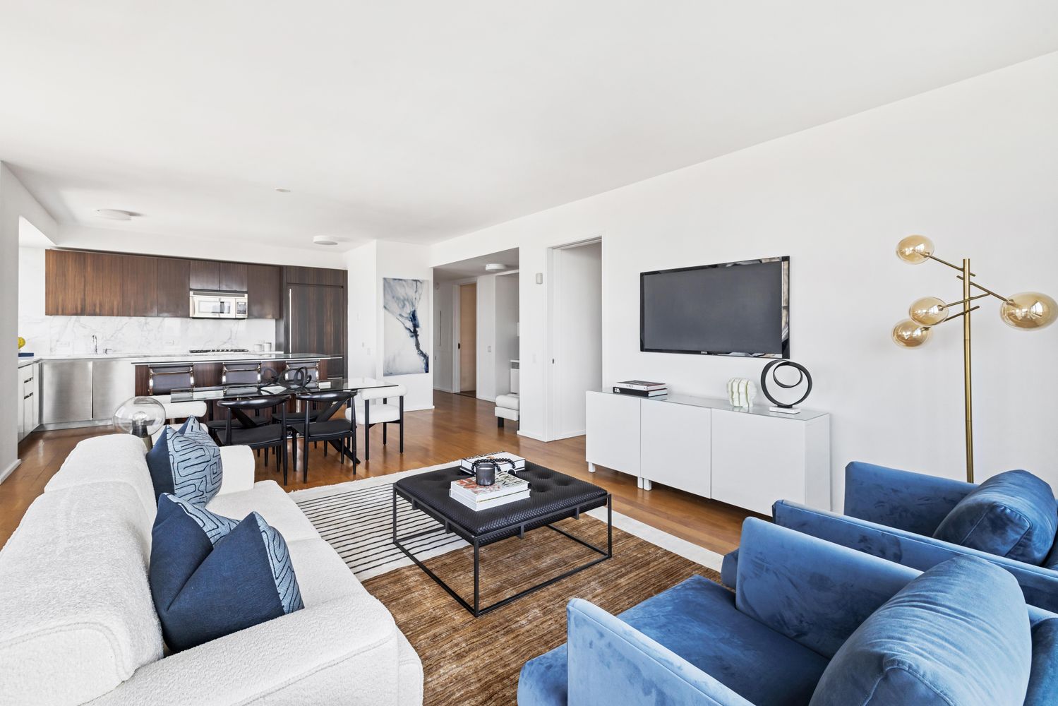 a living room with furniture a flat screen tv and kitchen view