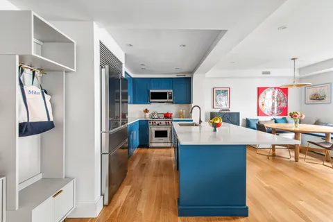 a living room with furniture kitchen view and a wooden floor