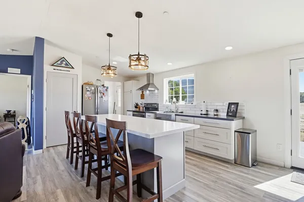 a view of a dining room and livingroom with furniture wooden floor a rug a painting and a chandelier