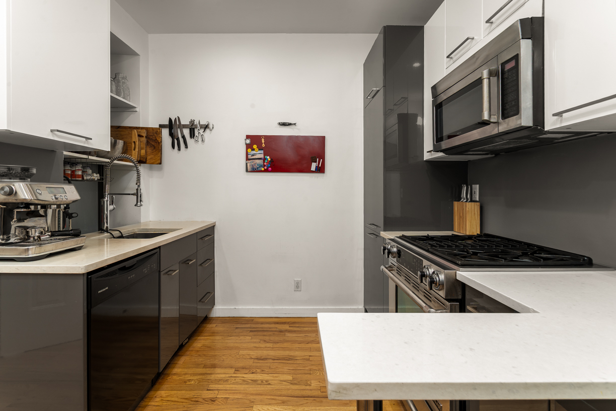 119 East 101st Street, Unit 1A Manhattan, NY 10029 - Photo 5 of 10 a kitchen with stainless steel appliances a stove a microwave a sink and cabinets