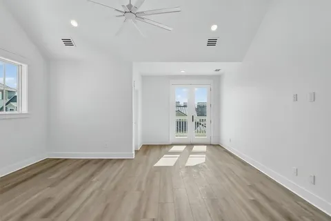 an empty room with cabinet wooden floors and a ceiling fan