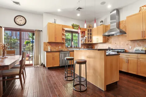 a kitchen with stainless steel appliances granite countertop a refrigerator a stove top oven a sink dishwasher and white cabinets with wooden floor