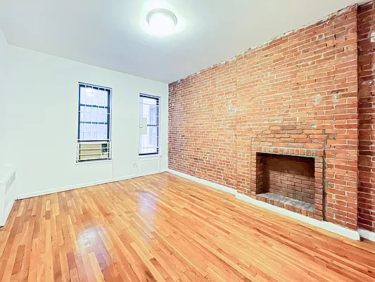 1734 2nd Avenue, Unit 1D Manhattan, NY 10128 - Photo 2 of 5 a view of an empty room with wooden floor fireplace and a window