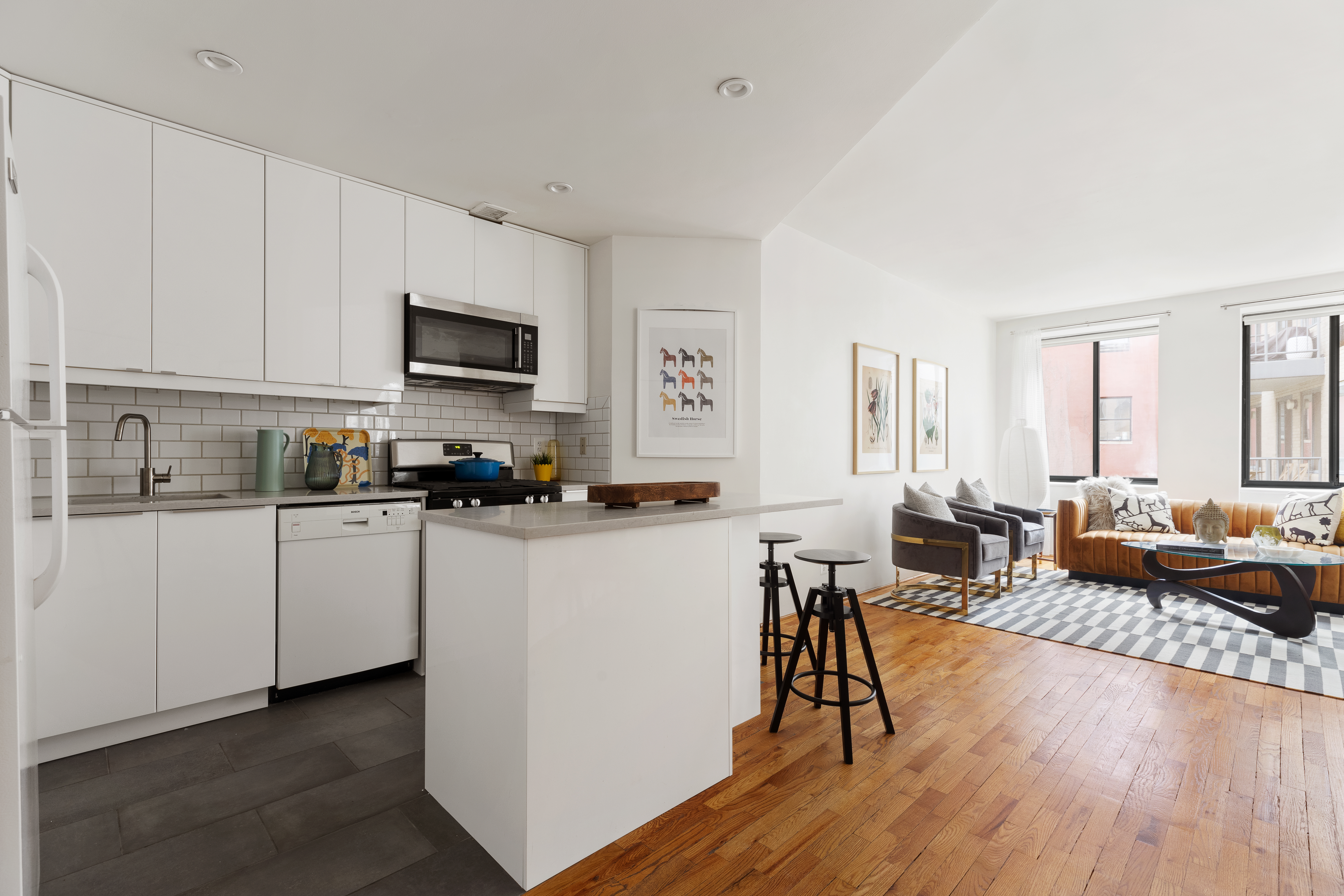 167 Perry Street, Unit 4K Manhattan, NY 10014 - Photo 1 of 11 a kitchen with stainless steel appliances a refrigerator a stove a sink a dining table and chairs with wooden floor