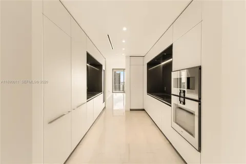 a hallway with hardwood floor and chandelier