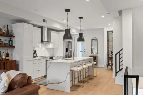 a kitchen with stainless steel appliances kitchen island granite countertop a stove a sink a refrigerator and white cabinets with wooden floor