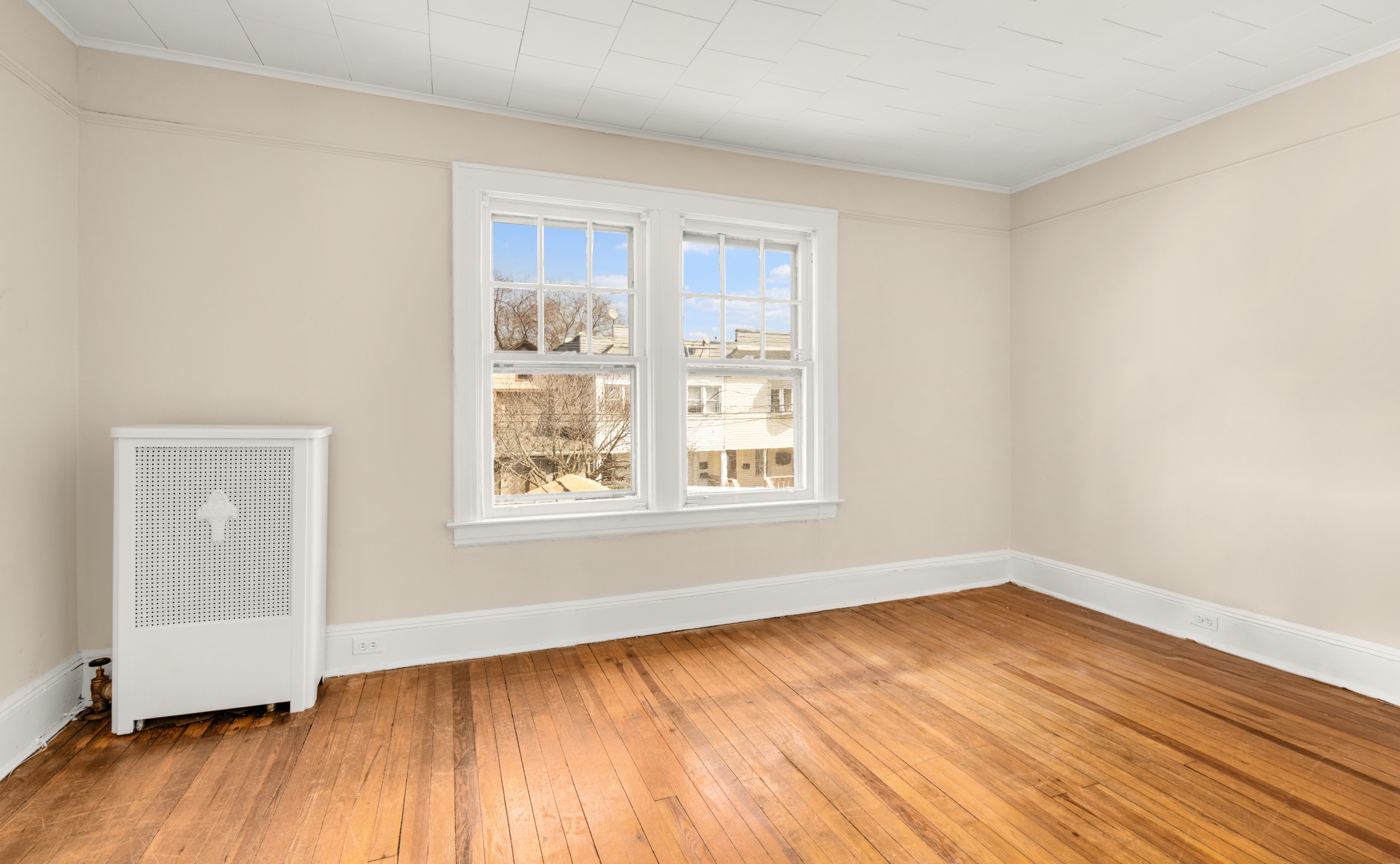 107-28 118th Street Queens, NY 11419 - Photo 8 of 12 a view of an empty room with wooden floor and a window
