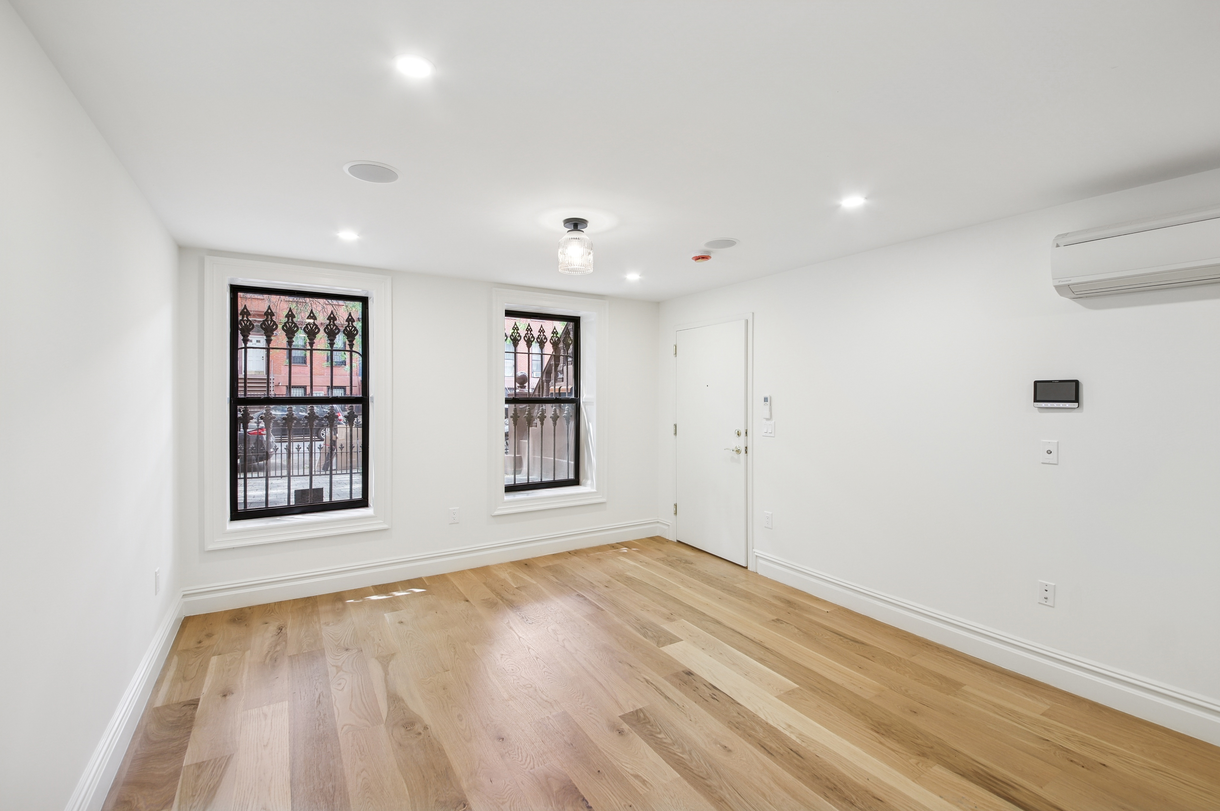 239 Madison Street, Unit 1 Brooklyn, NY 11216 - Photo 12 of 14 a view of an empty room with a window and wooden floor
