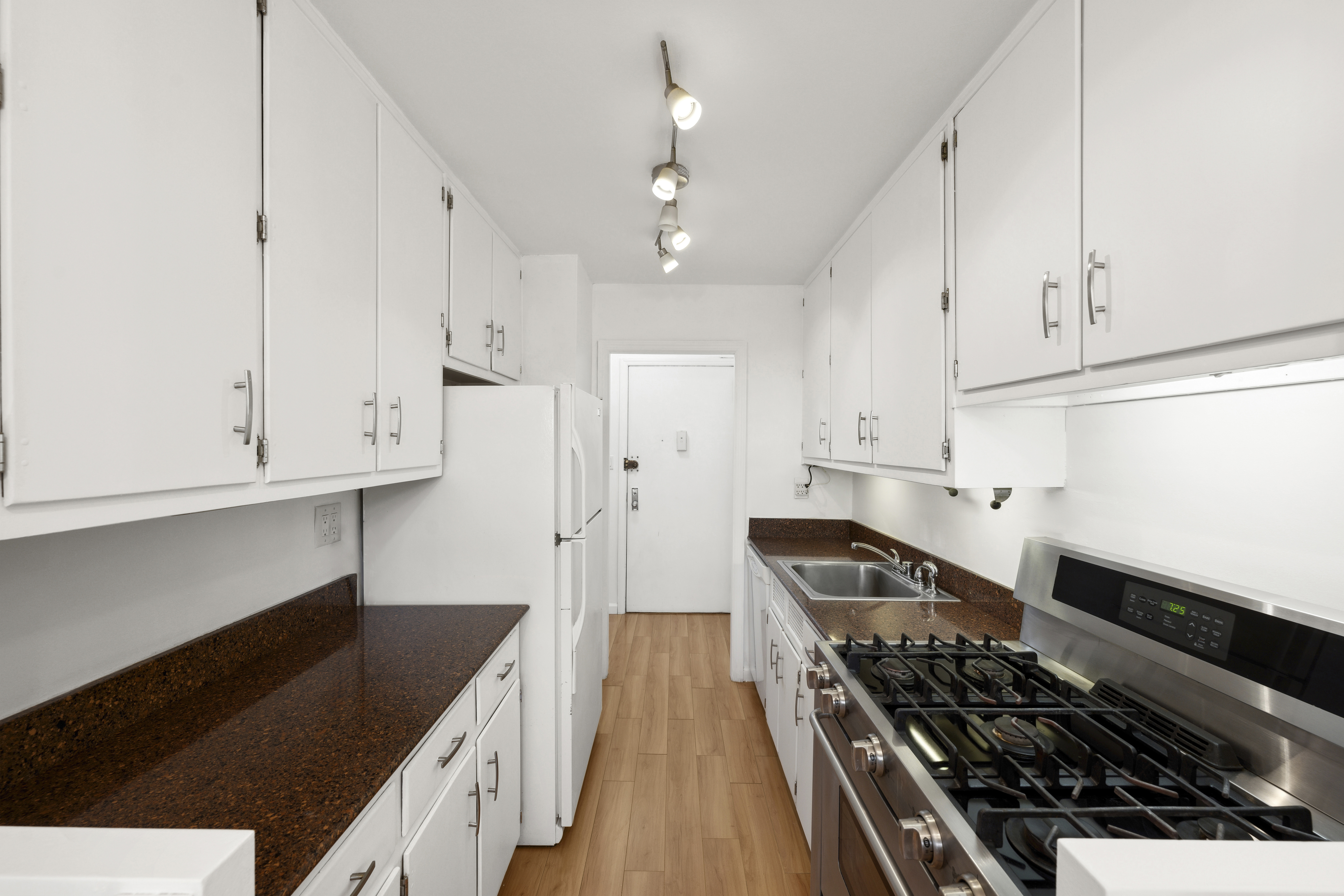 303 West 66th Street, Unit 2AE Manhattan, NY 10023 - Photo 8 of 15 a kitchen with granite countertop a stove and white cabinets