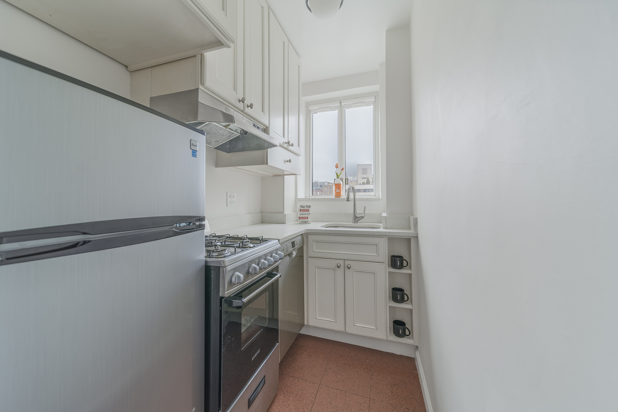 200 West 20th Street, Unit 1208 Manhattan, NY 10011 - Photo 11 of 14 a kitchen with white cabinets and white appliances