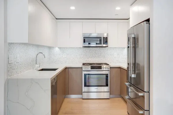 a kitchen with stainless steel appliances granite countertop a refrigerator sink and stove