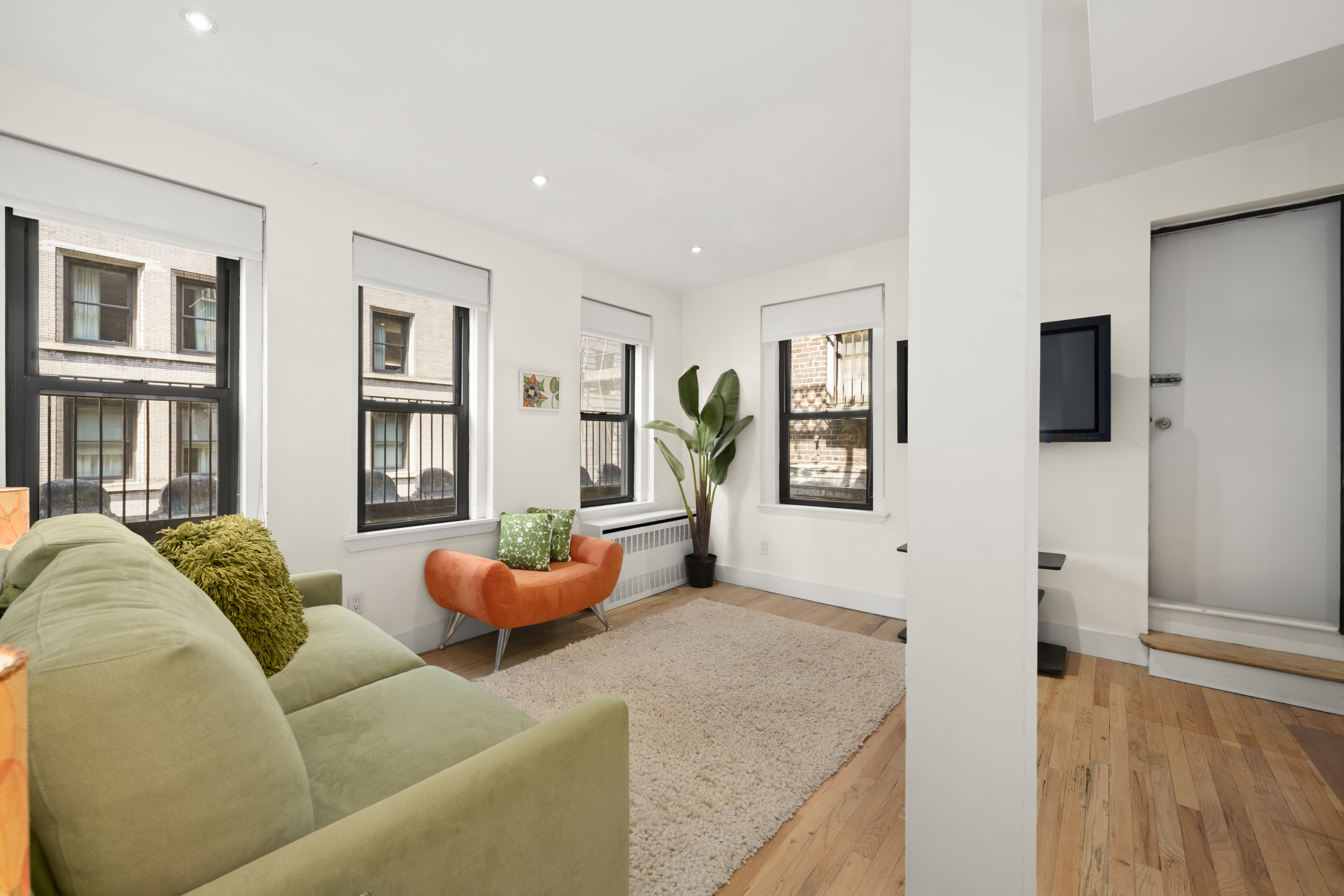 176 Broadway, Unit 9F Manhattan, NY 10038 - Photo 3 of 9 a living room with furniture and a flat screen tv