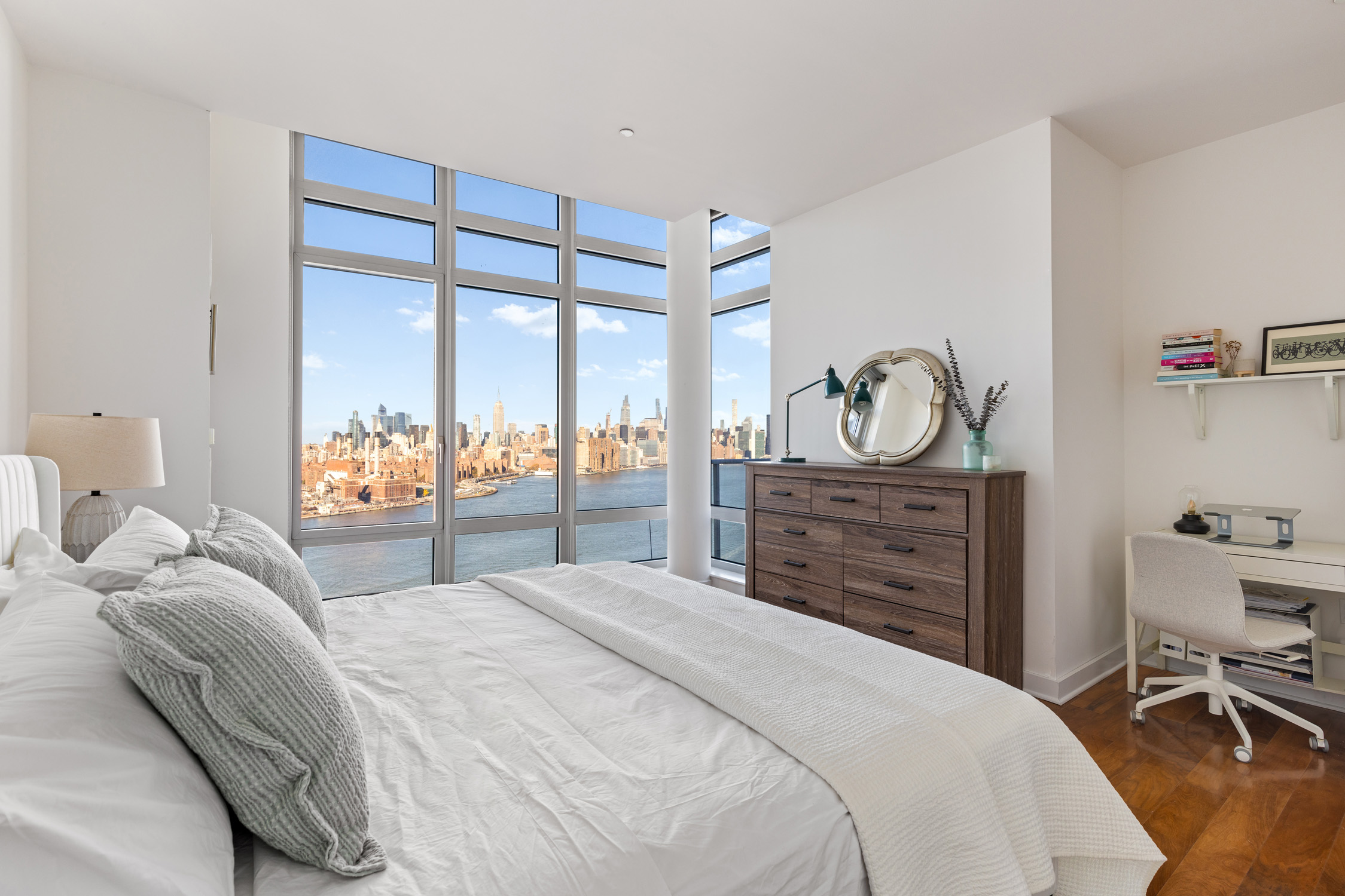 2 Northside Piers, Unit 31P Brooklyn, NY 11249 - Photo 6 of 16 a bedroom with a bed a table and a large mirror with a bookshelf