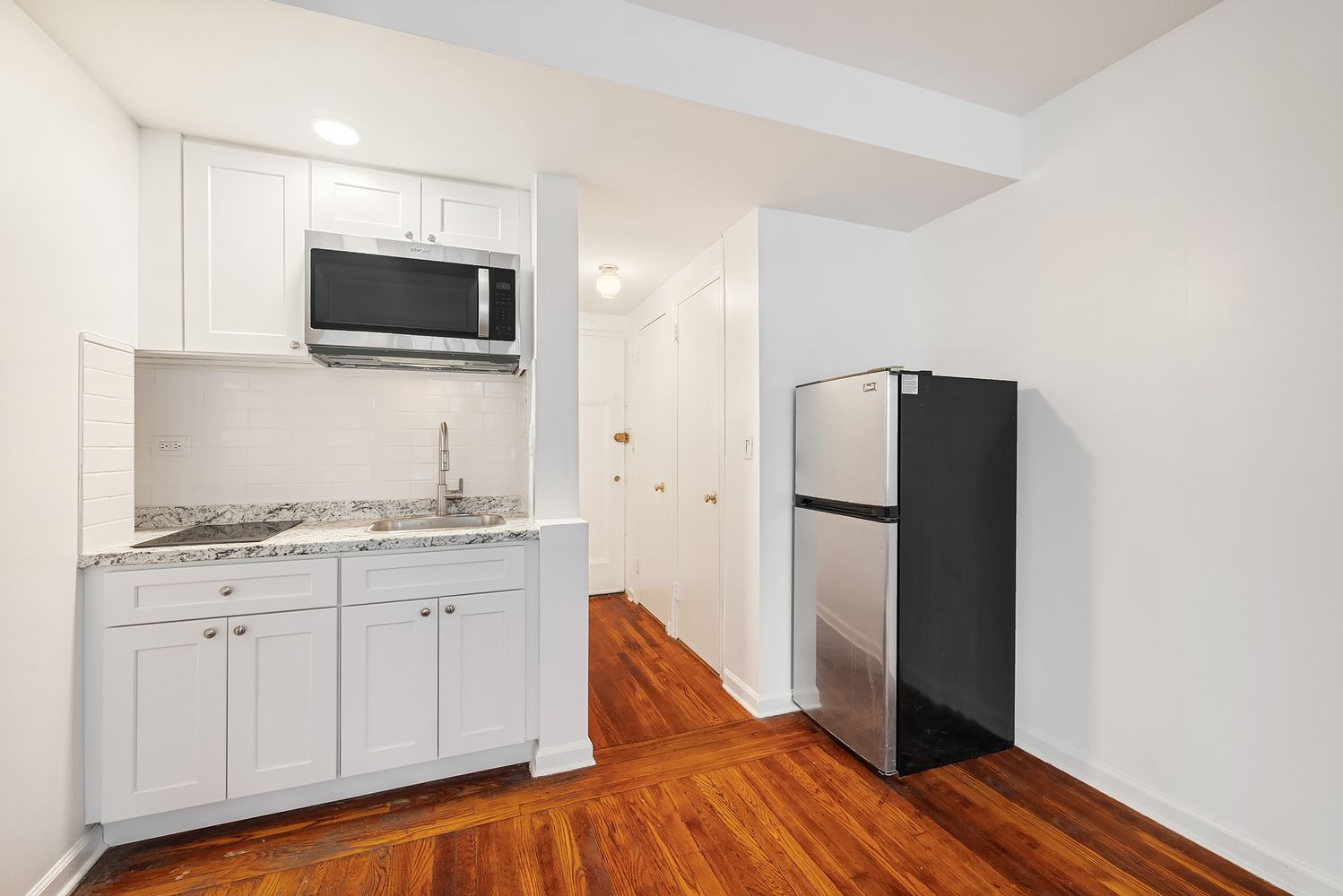 320 East 42nd Street, Unit 407 Manhattan, NY 10017 - Photo 2 of 3 a kitchen with a refrigerator and microwave