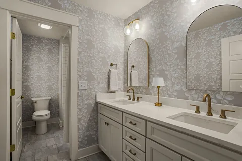 a bathroom with a double vanity sink toilet and a mirror