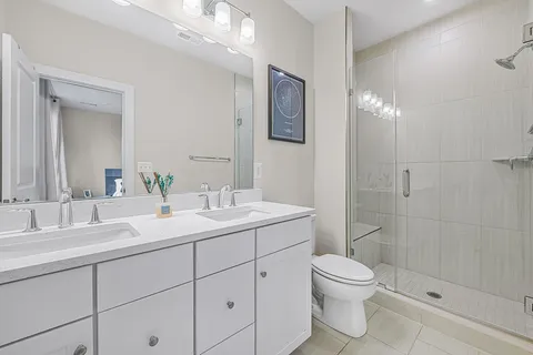 a bathroom with a toilet a sink a mirror a shower a vanity and window