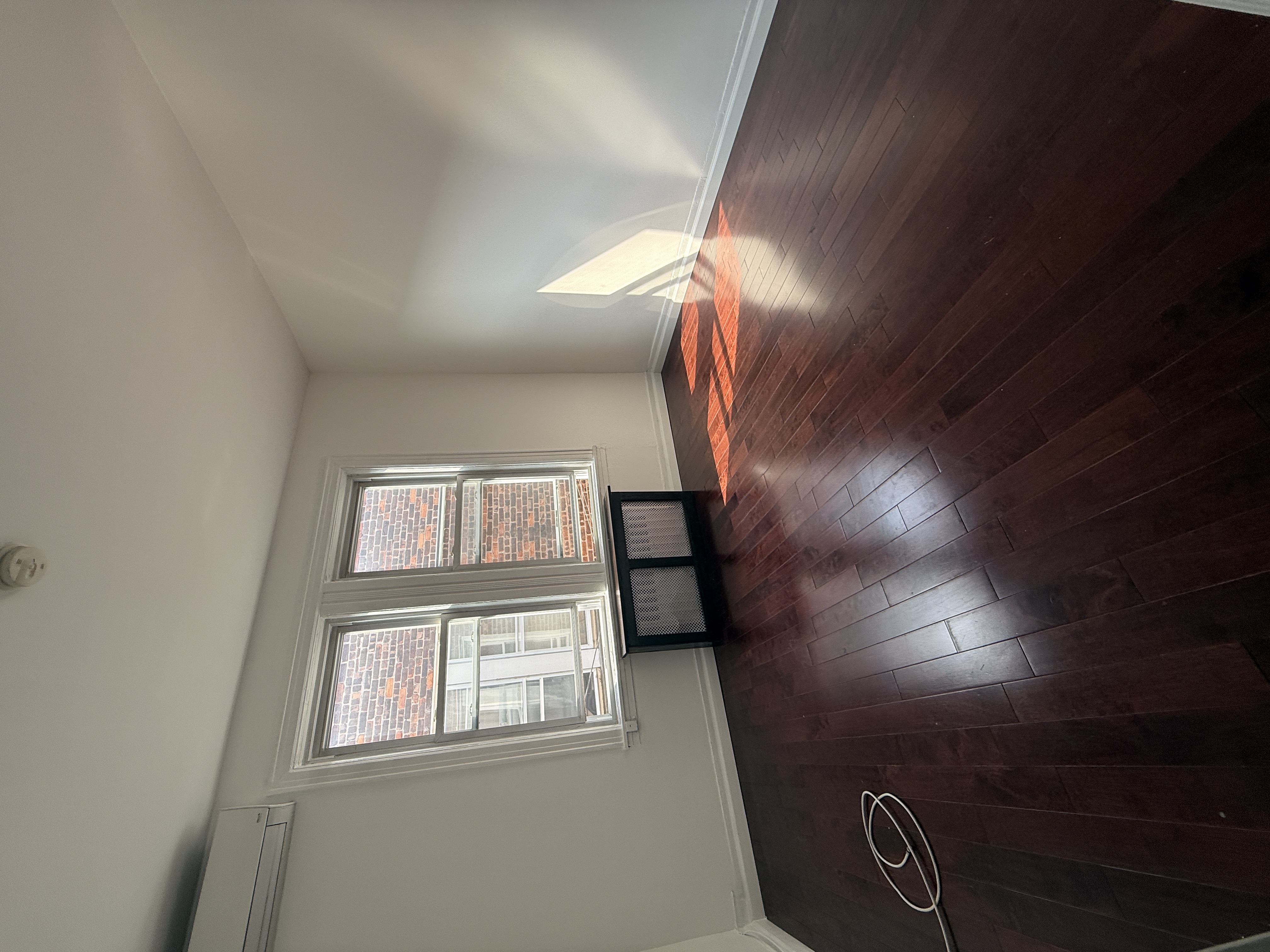 18-48 21st Drive, Unit 2R Queens, NY 11105 - Photo 3 of 7 a view of an empty room with wooden floor and a window
