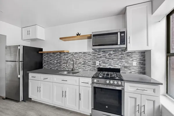 a kitchen with white cabinets and stainless steel appliances
