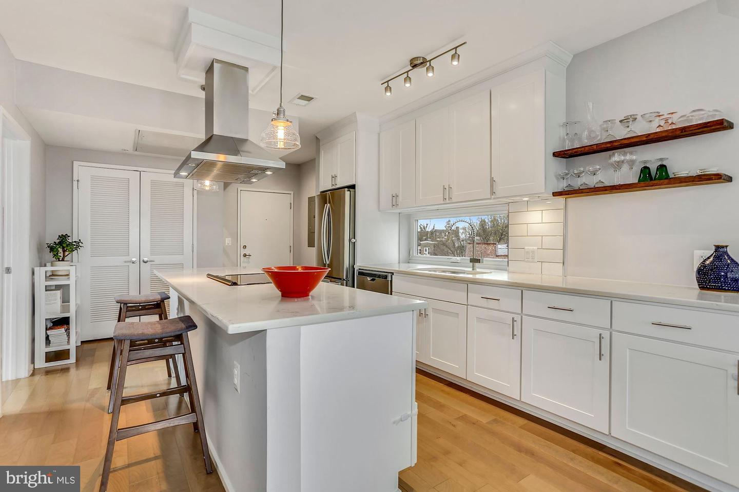 129 Varnum Street Northwest, Unit 6 Washington, DC 20011 - Photo 7 of 25 a room with kitchen island a sink dishwasher a stove a dining table and chairs with wooden floor