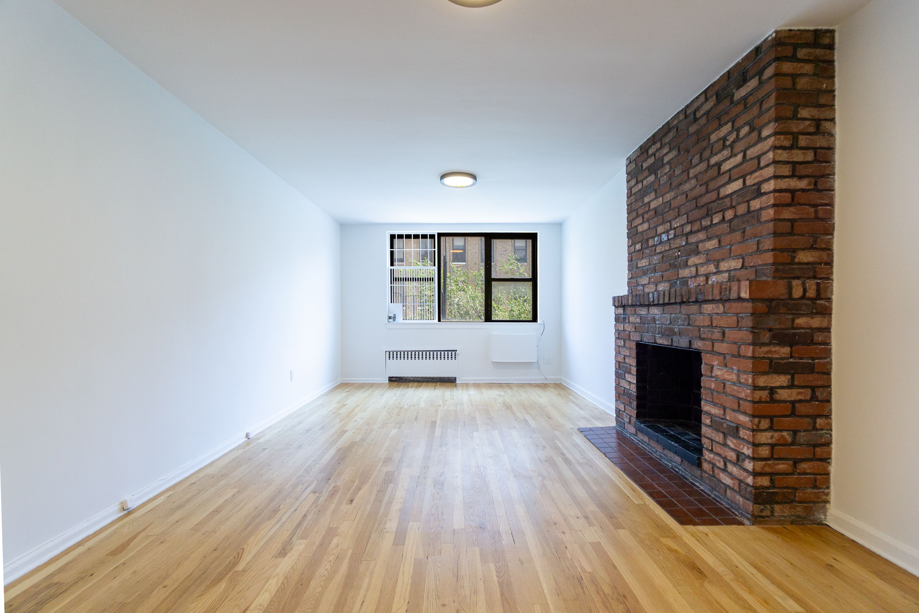 an empty room with wooden floor fireplace and windows
