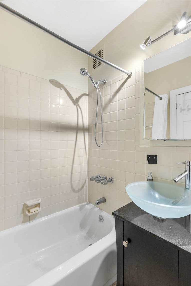 313 East 89th Street, Unit 4C Manhattan, NY 10128 - Photo 4 of 8 a bathroom with a sink a mirror and a bathtub