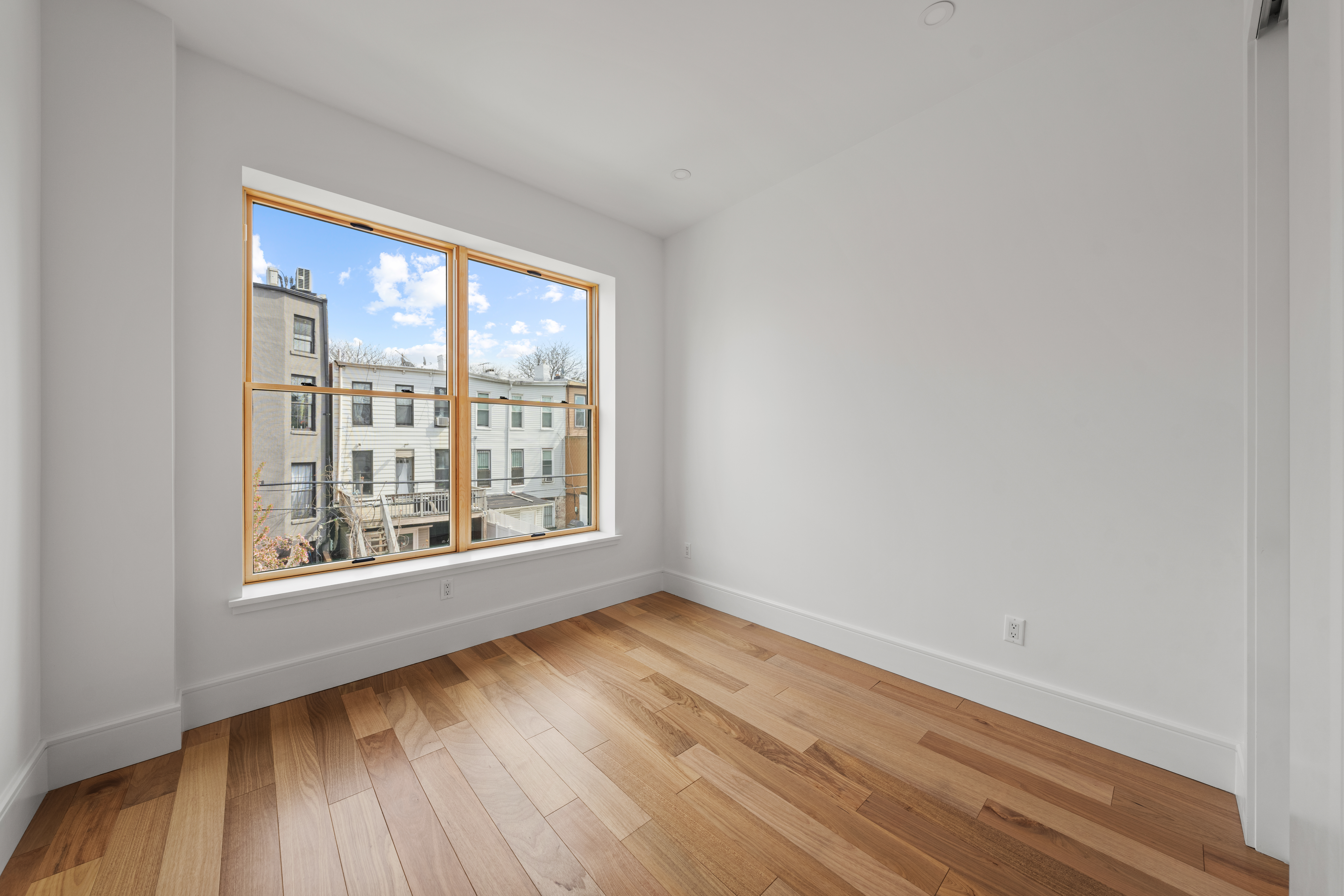 82 Cooper Street, Unit 2B Brooklyn, NY 11207 - Photo 12 of 17 a view of an empty room with wooden floor and a window
