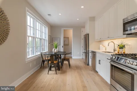 a kitchen with stainless steel appliances a dining table chairs stove refrigerator and cabinets