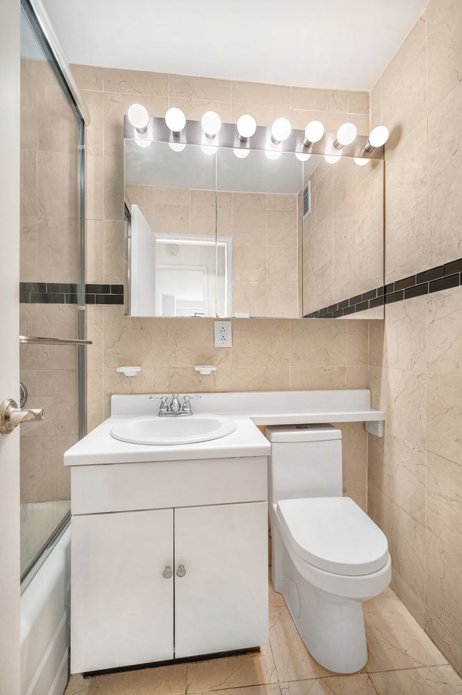 345 East 73rd Street, Unit 3A Manhattan, NY 10021 - Photo 5 of 7 a bathroom with a sink a toilet and a mirror