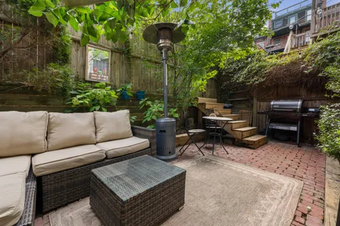 a view of a patio with couches and a fire pit and wooden fence