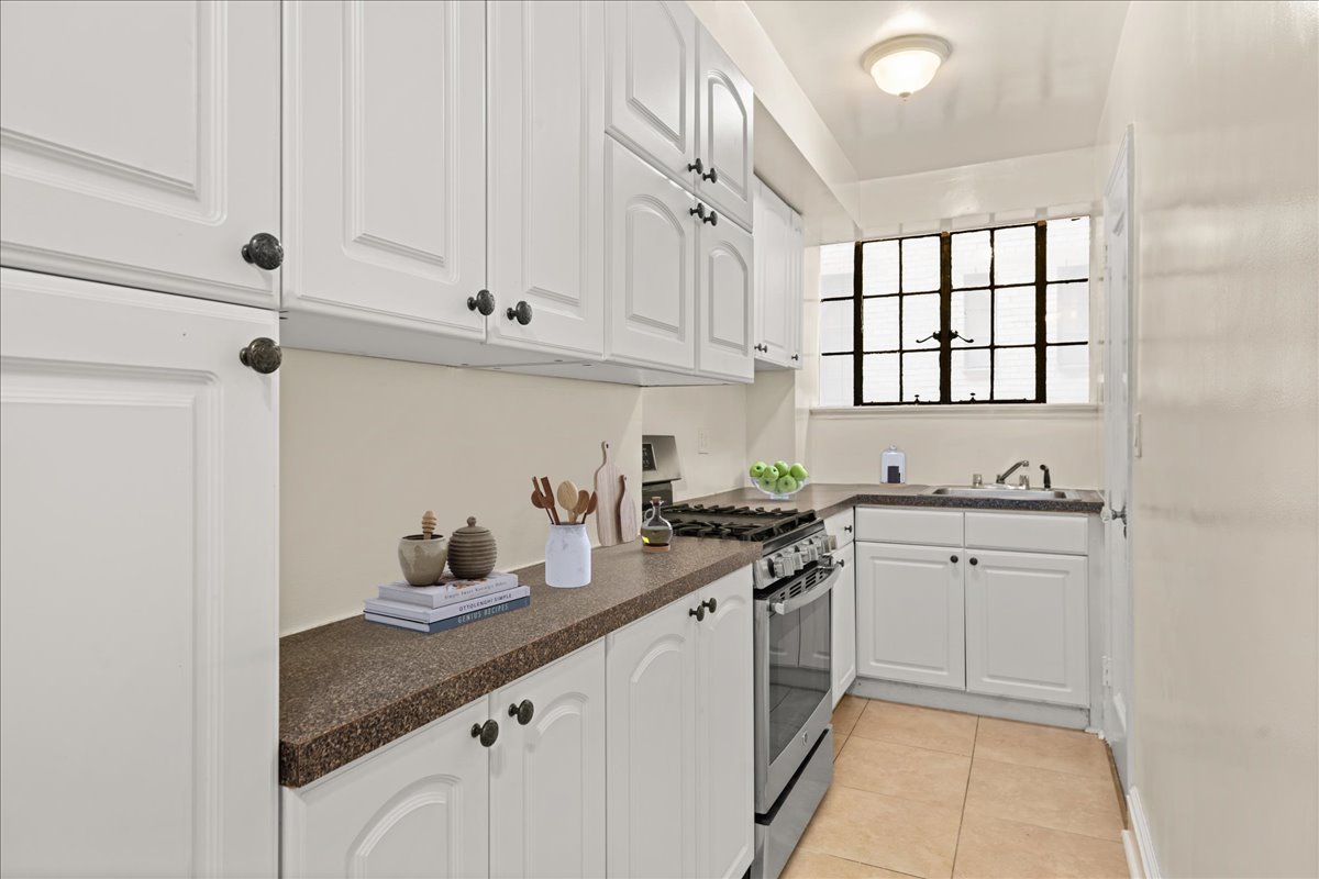 325 East 41st Street, Unit 605 Manhattan, NY 10017 - Photo 3 of 7 a kitchen with granite countertop white cabinets and white appliances