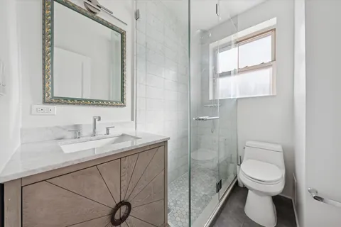 a bathroom with a granite countertop toilet sink and mirror