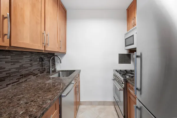a kitchen with granite countertop a sink stove and refrigerator