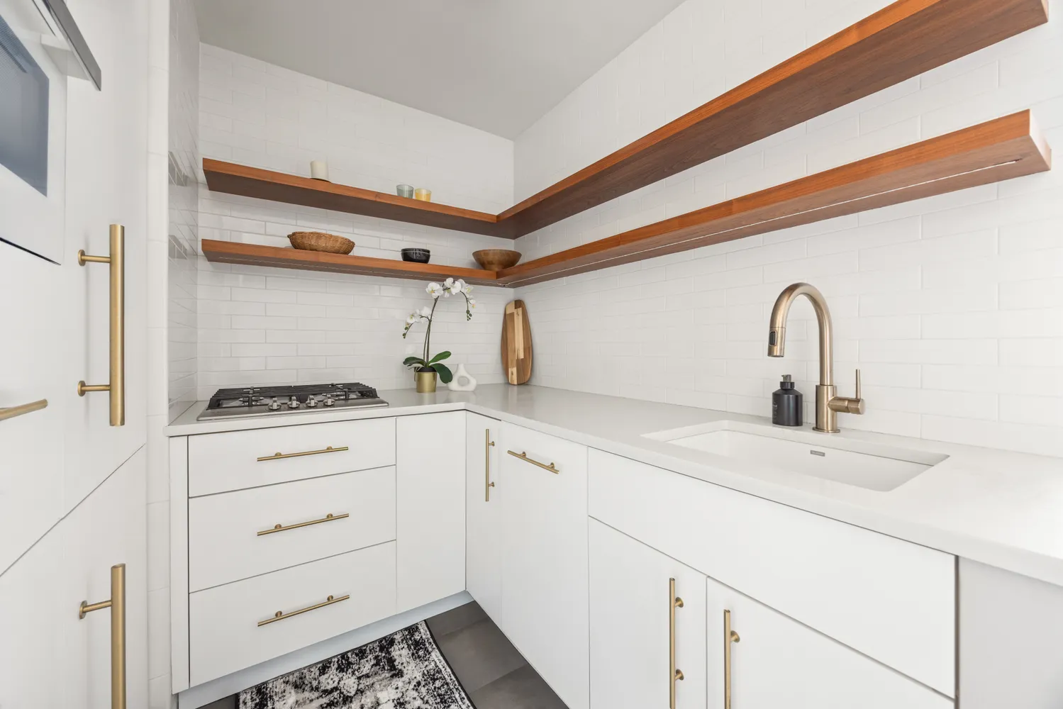 a close view of a stove a sink and dishwasher with white cabinets