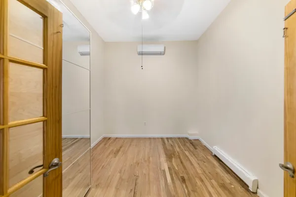 a view of a room with wooden floor a ceiling fan and window