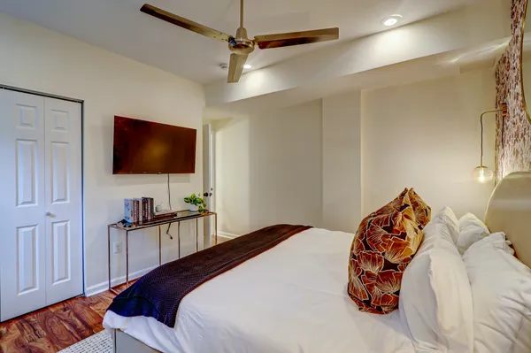 a bedroom with a bed and a flat tv screen on the dresser