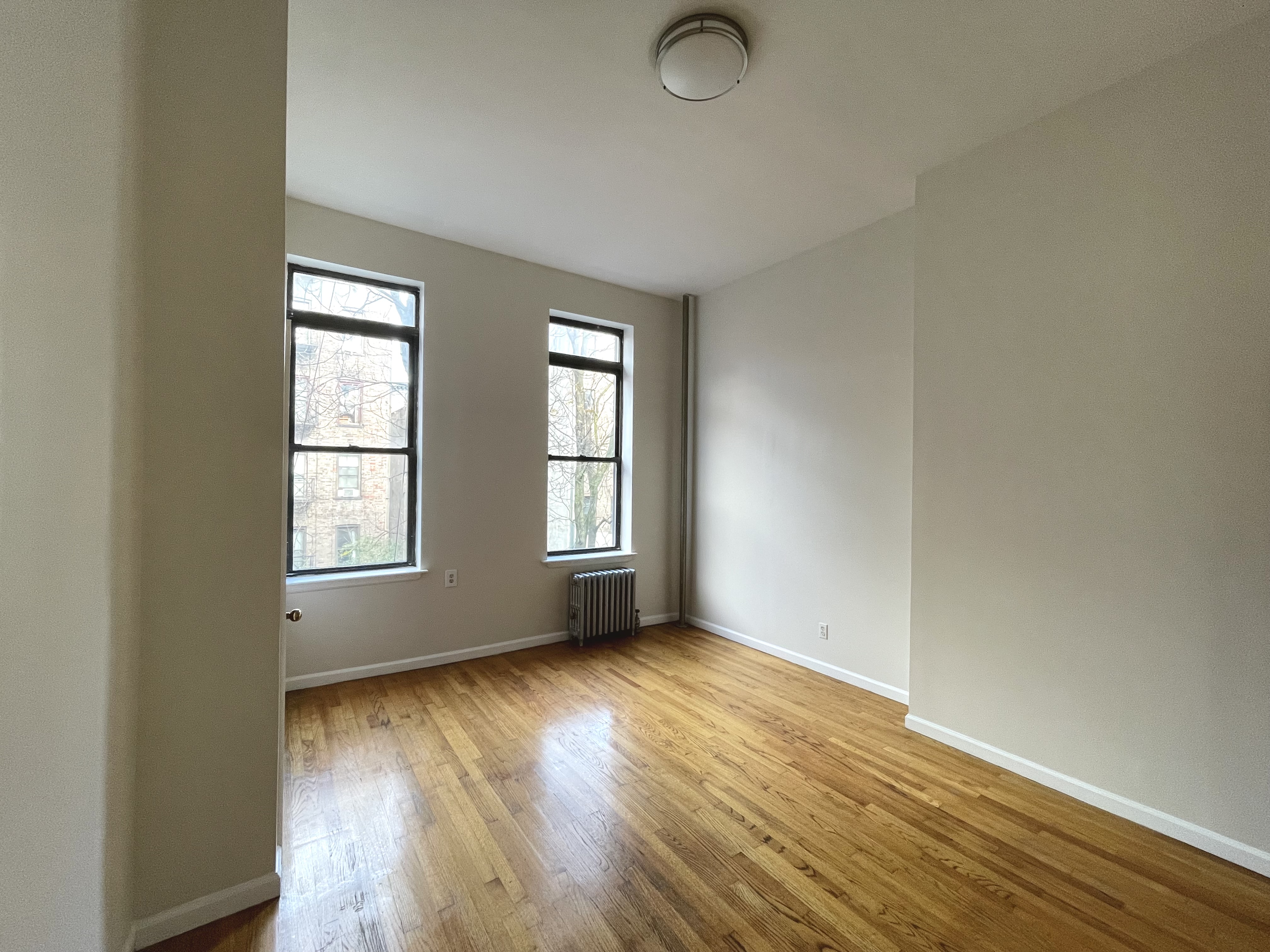 95 St Marks Place, Unit 6 Manhattan, NY 10009 - Photo 11 of 14 an empty room with wooden floor and windows