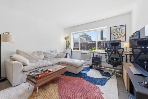 a living room with furniture a rug and a floor to ceiling window