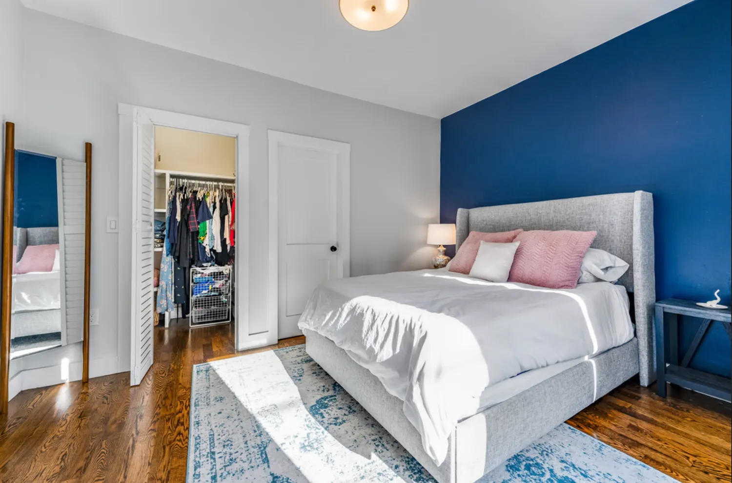a bedroom with a bed and a dresser with wooden floor