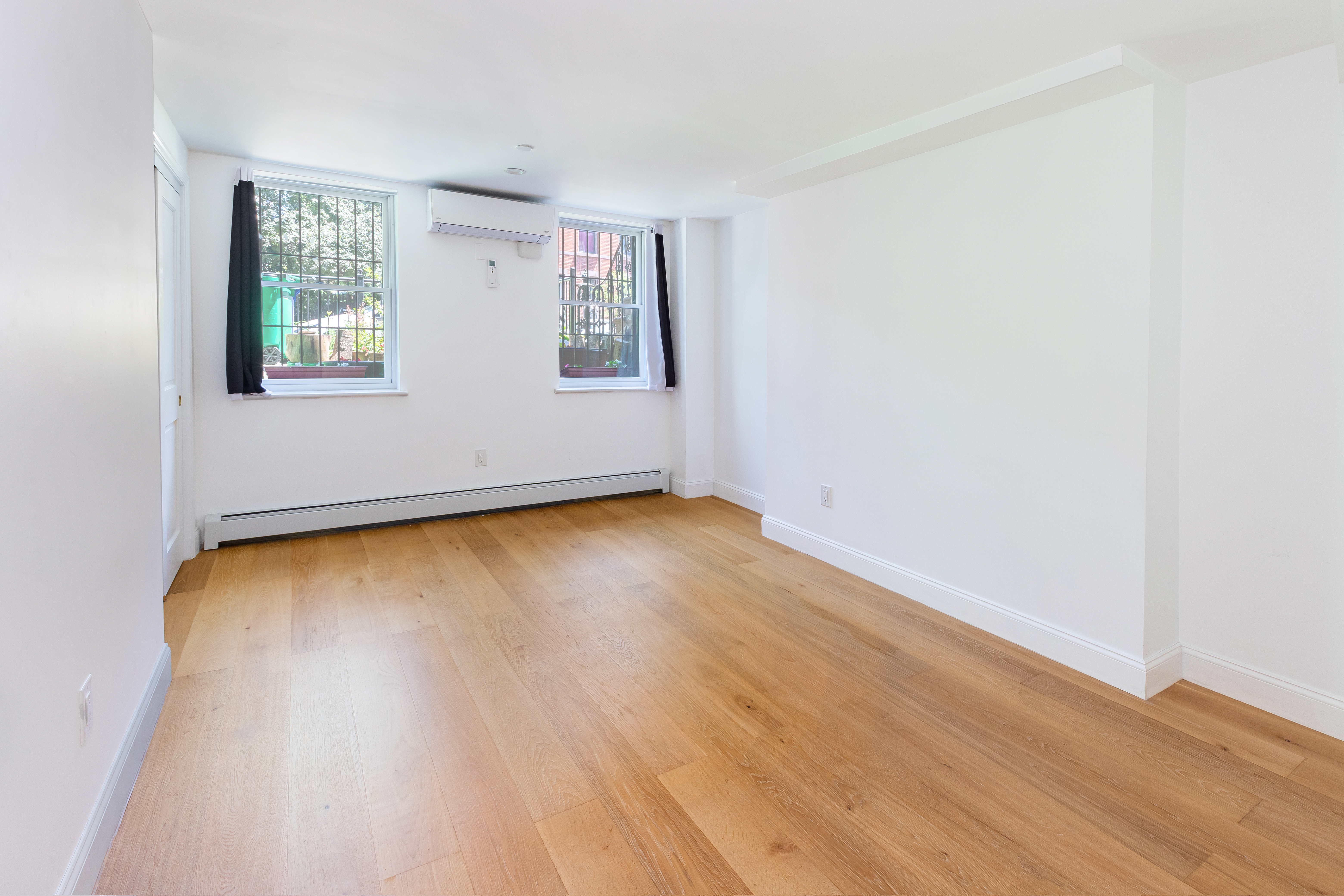 492 Warren Street, Unit GARDEN Brooklyn, NY 11217 - Photo 4 of 8 an empty room with wooden floor and windows