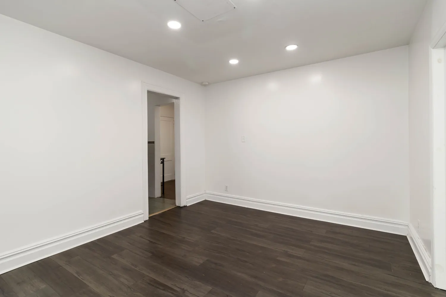 a view of an empty room with wooden floor and closet