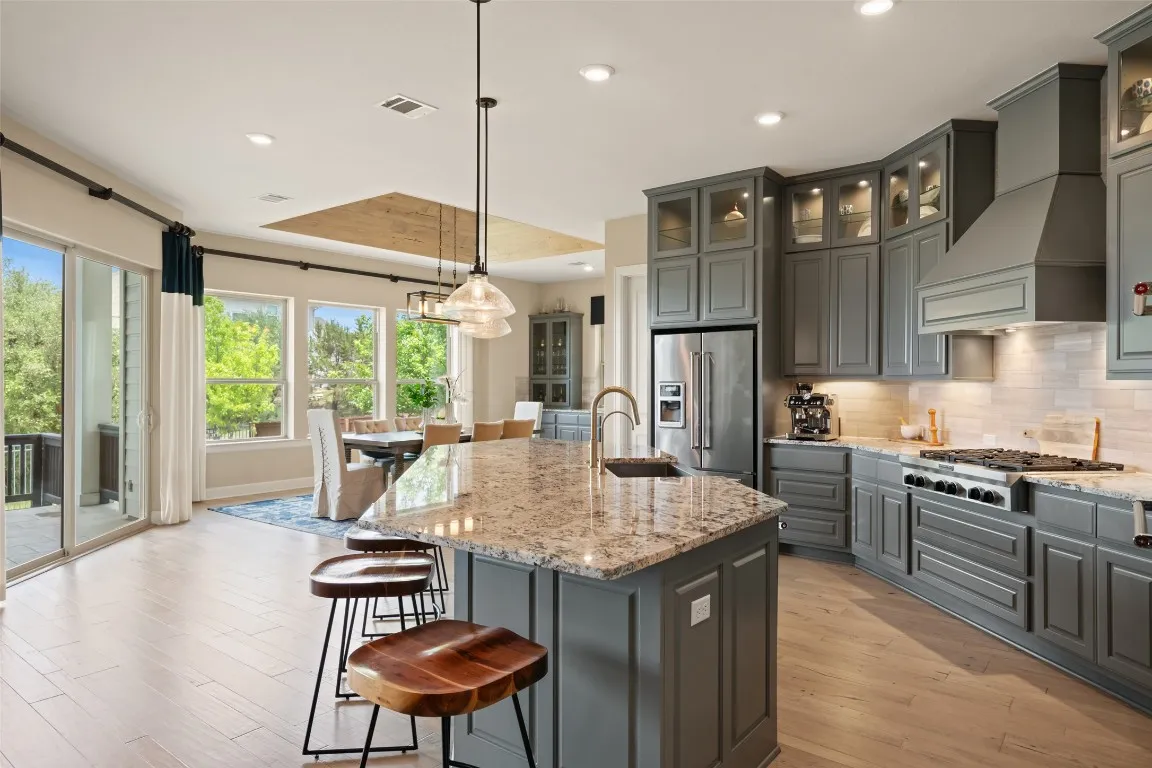 a kitchen with granite countertop kitchen island stainless steel appliances a table chairs sink and wooden floor