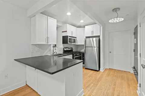 a kitchen with refrigerator a microwave a sink and white cabinets