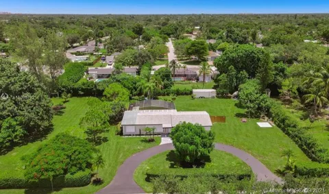 an aerial view of residential houses with outdoor space and trees