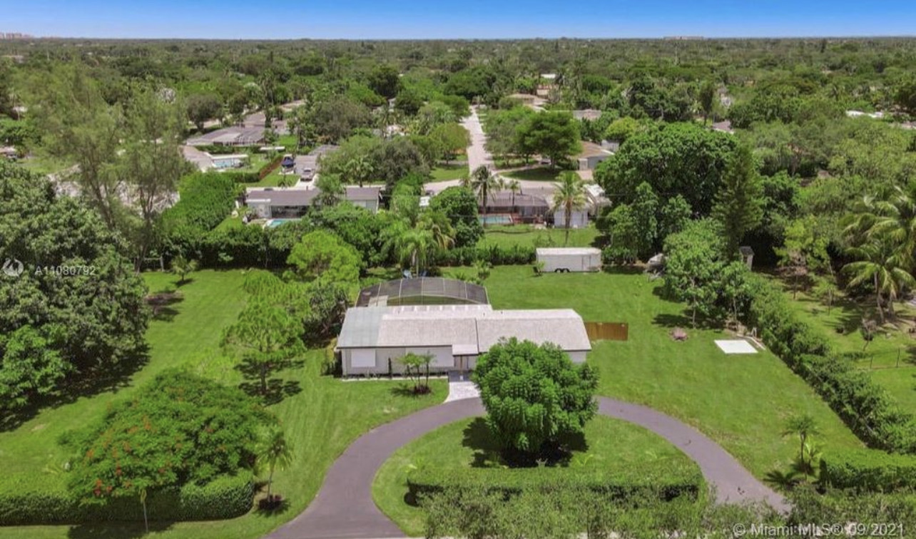 an aerial view of residential houses with outdoor space and trees